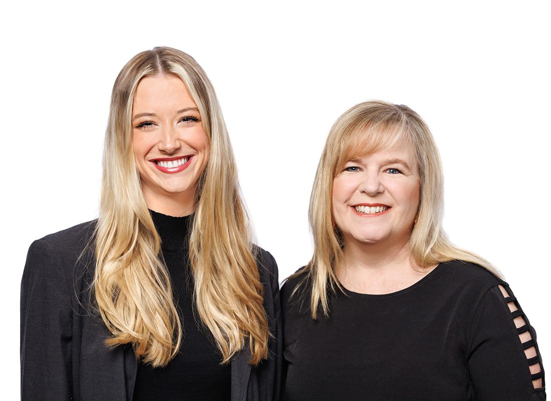 About Our Agency - Smiling Portrait of Leslie and Grace from Ward Insurance Group Wearing Black Standing Against a White Wall